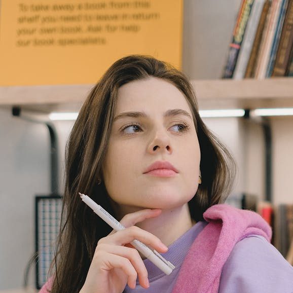 thoughtful young lady looking away while doing assignment in classroom
